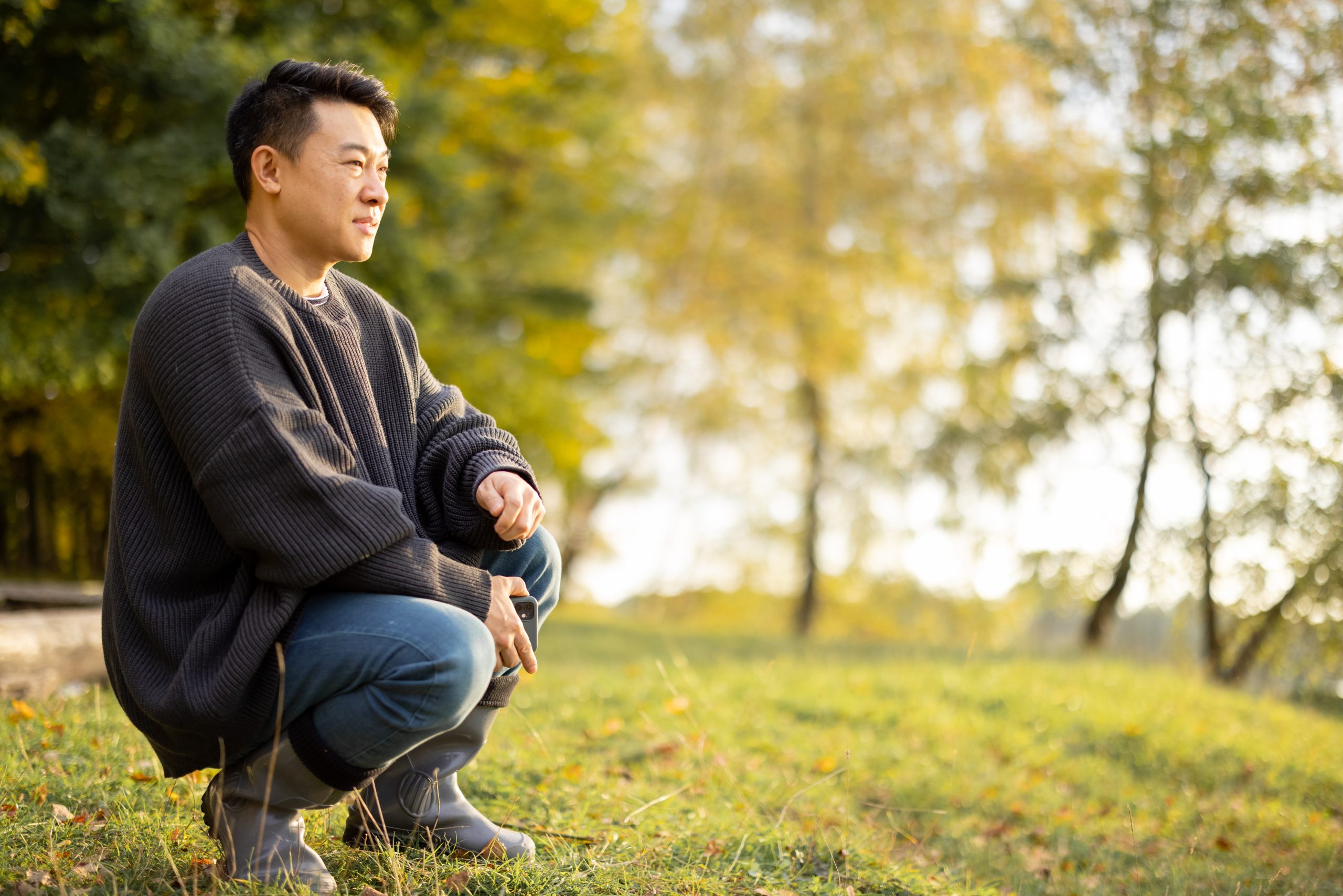 Man squatting in the grass enjoying nature