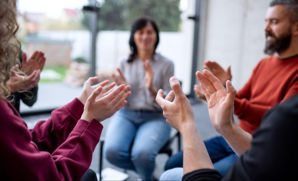  People clapping in a circle. 