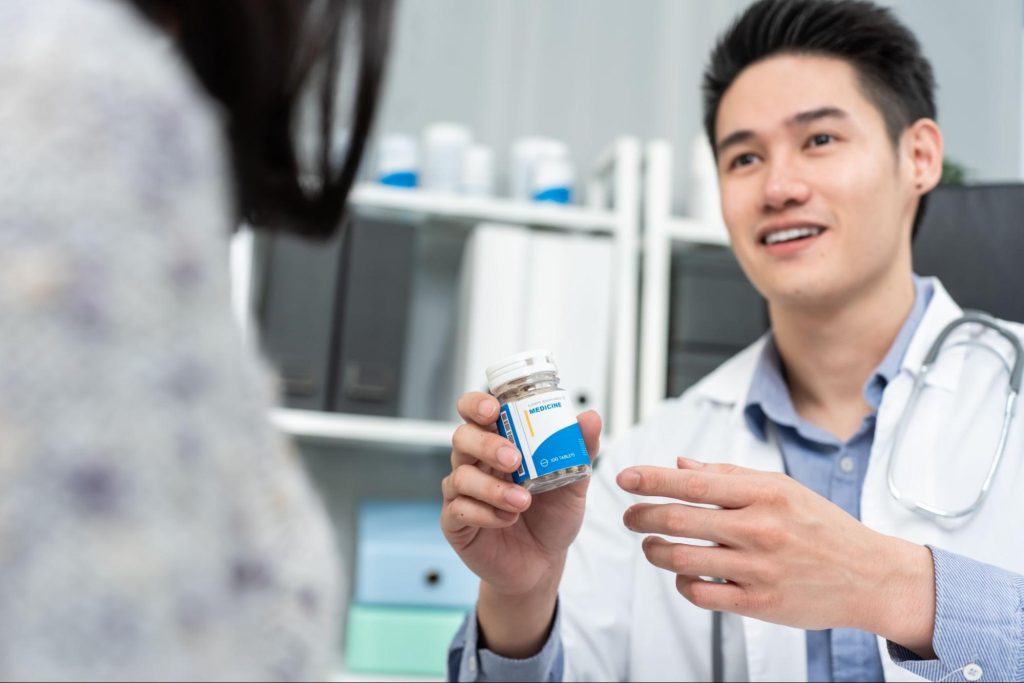 A male doctor is giving prescribed pills to a female patient.