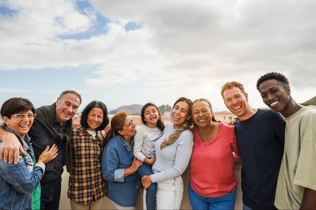 Family and friends smiling and standing outside.