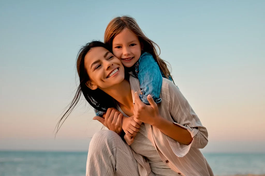 Mother and daughter smiling and enjoying time on the beach